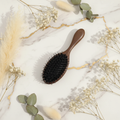 Brosse à cheveux en poils de sanglier CHAARNA posée sur marbre avec plantes
