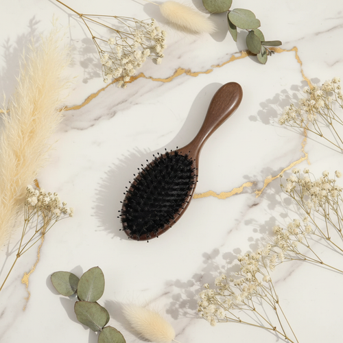 Brosse à cheveux en poils de sanglier CHAARNA posée sur marbre avec plantes
